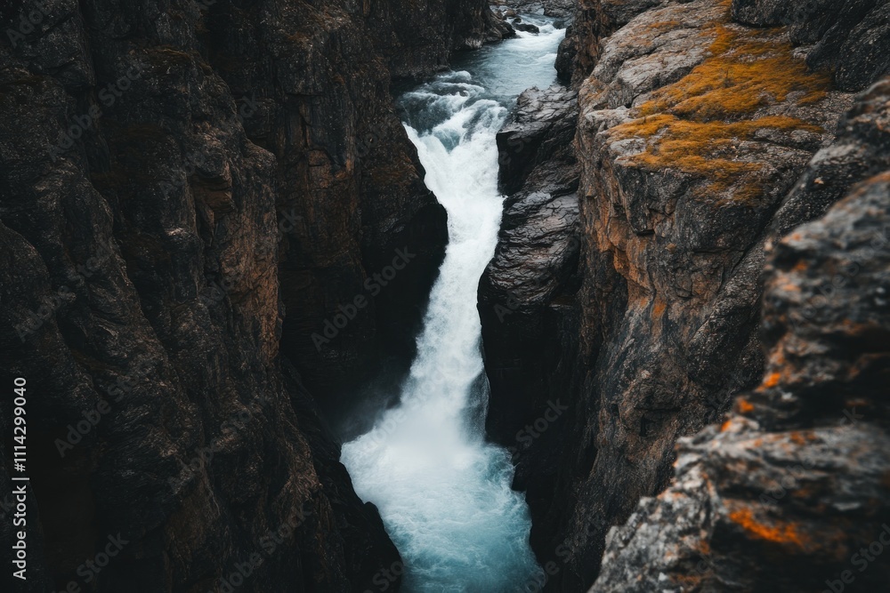 Obraz premium Powerful Waterfall Plunges Through Dark Rocky Gorge
