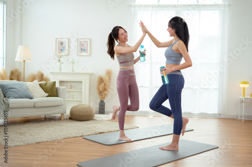 Two young Asian woman friends relaxing after doing Yoga at home.