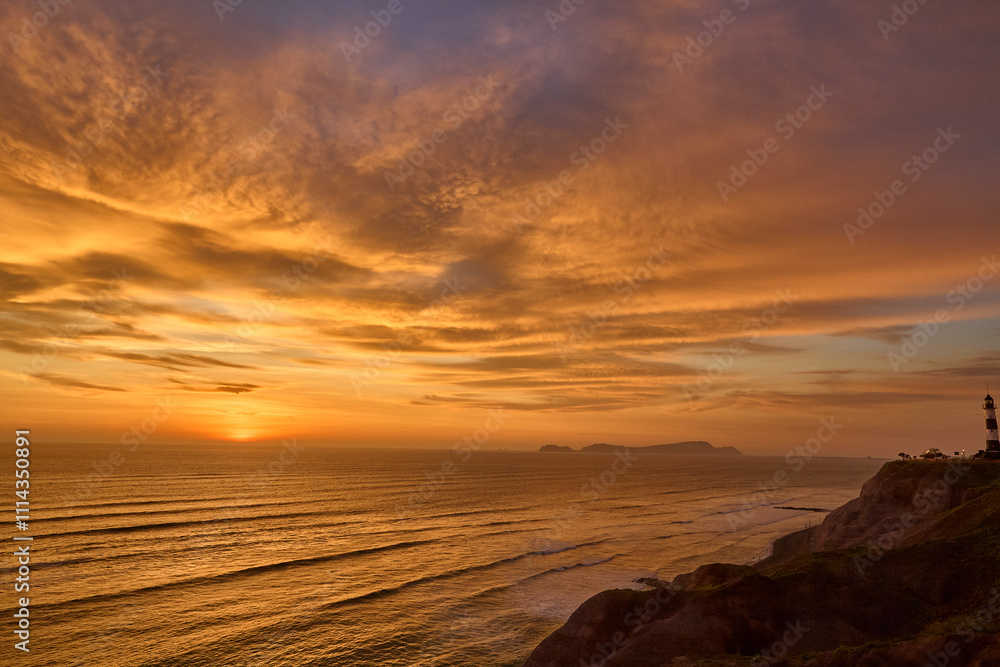 Obraz premium As the sun sets over San Lorenzo Island, the view from Miraflores becomes pure magic .The island silhouettes against a sky ablaze with color, while the ocean whispers of infinite horizons. 