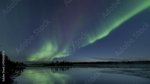Auroras starting to dance at dusk above a still lake