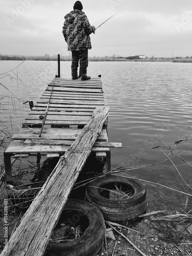 old man fishing on a wooden pier by the river photo