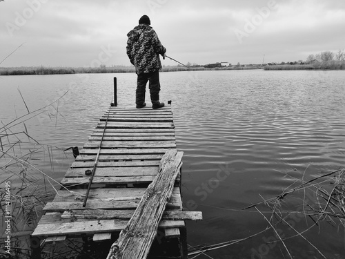 old man fishing on a wooden pier by the river photo