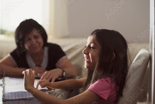 Grandmother at home helps granddaughter to do homework