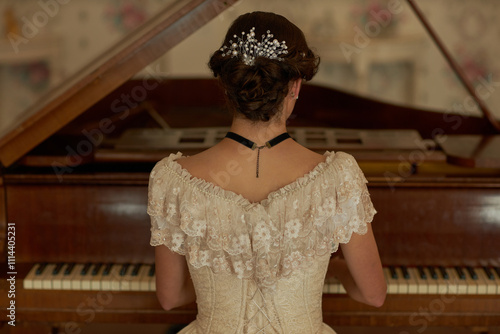 Canvas Print Back view of classic young lady wearing lace dress with pearls in hair playing g