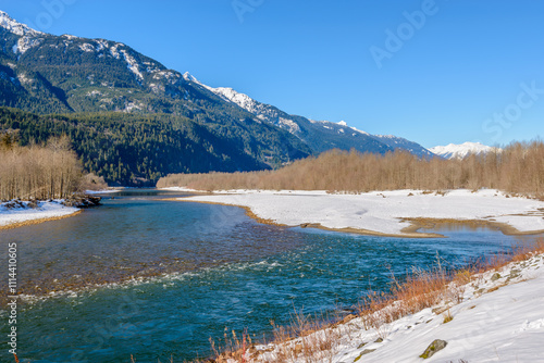 Majestic mountain river in winter over snow mountains and blue sky in Vancouver, Canada.