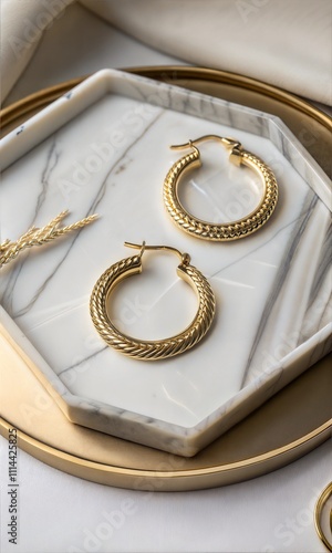 Overhead view of gold hoop earrings on a marble tray, top view of solid gold earrings on a marble jewelry holder photo