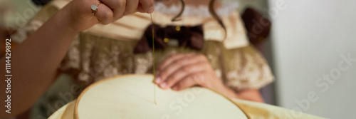 Header format close up of young lady guiding thread through fabric doing intricate embroidery in vintage setting, copy space photo