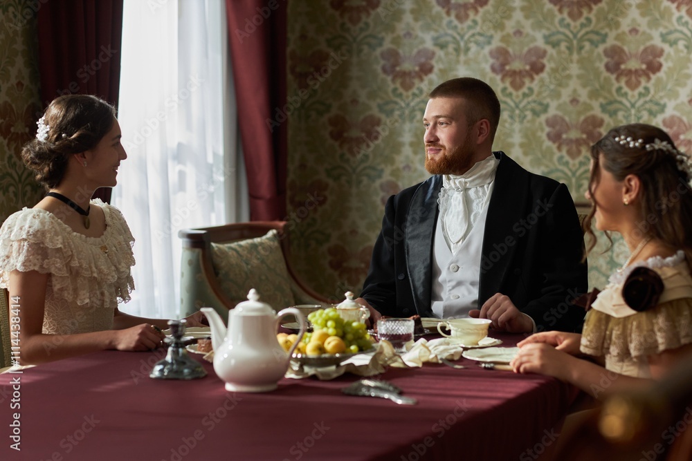 Portrait of classic gentleman enjoying tea with two young ladies sitting at table together in classic ornate room, copy space Portrait of classic gentleman enjoying tea with two young ladies sitting at table together in classic ornate room, copy space