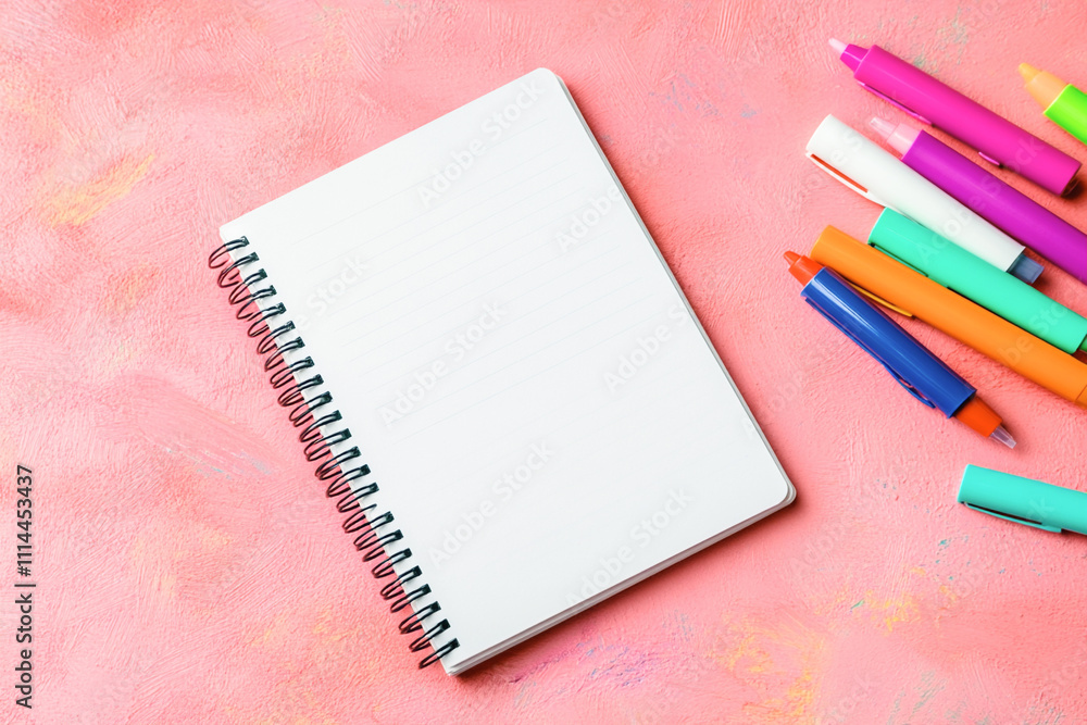 Spiral notebook with colorful pens on a bright pink textured background. Top view, flat lay, mock up Spiral notebook with colorful pens on a bright pink textured background. Top view, flat lay, mock up