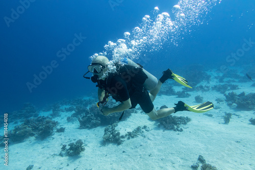 Obraz na płótnie Single scuba diver with the equipment over colorful coral reef on the sandy bottom of tropical sea, underwater landcape w salonie