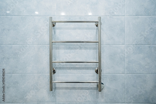 A modern stainless steel towel rack is elegantly hanging on a striking blue tiled wall, adding a stylish touch to the bathroom decor, enhancing both functionality and aesthetics photo