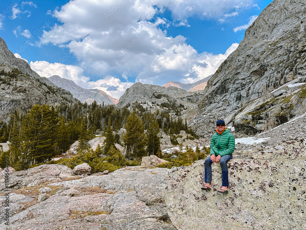 A young man sits on a rock in the Wind River Range of Wyoming. A young man sits on a rock in the Wind River Range of Wyoming.