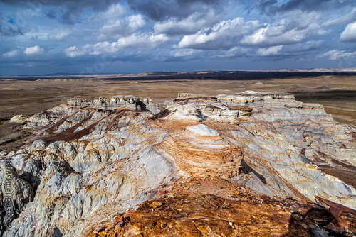 Kazakhstan, Mangistau, Mangyshlak, Kokala. Multicolored layered geological chalk formations among the remote Kazakh steppe under beautiful clouds