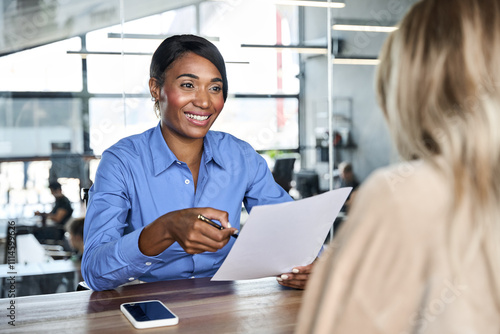 Happy African American young business woman hr talking to recruit at job interview meeting. Diverse female financial advisor, professional bank manager and client talking working in corporate office.