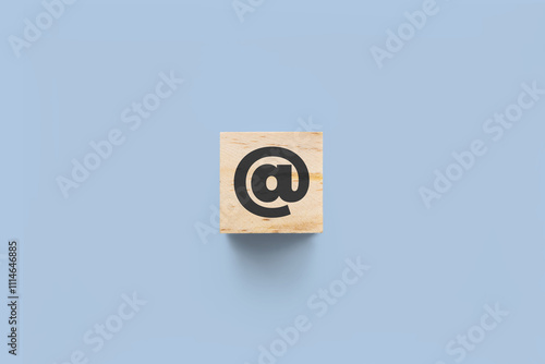 @ (at) wooden cube on blue background