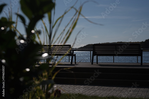 LANDSCAPE BY LAKE - Benches on the viewing and recreational platform in the sun rays photo