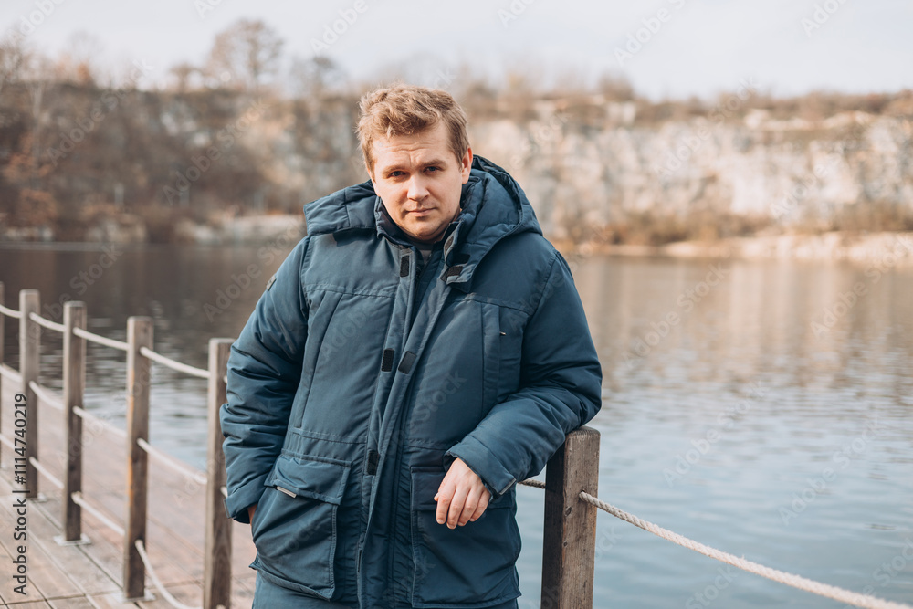 Fototapeta premium A blonde man walks on a bridge into a river. Autumn time. Freedom and active lifestyle concept. Male Spending time alone in nature.