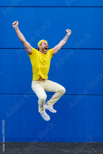 Man in yellow outfit expressing joy against blue background photo