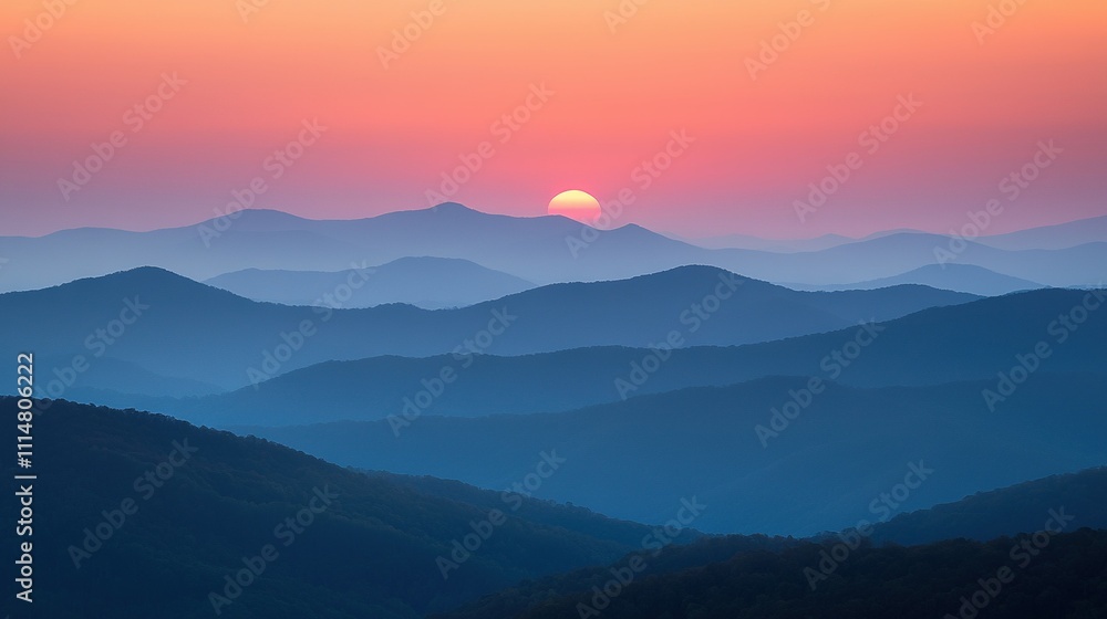Fototapeta premium The sun sets behind the mountains, casting a hazy sky in both the foreground and background