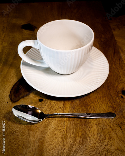 A white coffee cup and saucer sit on a wooden table