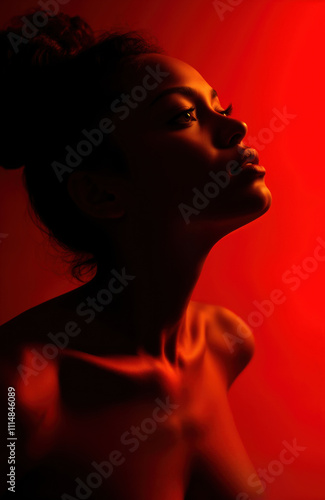 Dark-skinned woman gazes sideways against red backdrop. Intense emotion, beauty conveyed through lighting, pose. Sensual, mysterious portrait. Dramatic lighting creates shadows, highlights. Model,