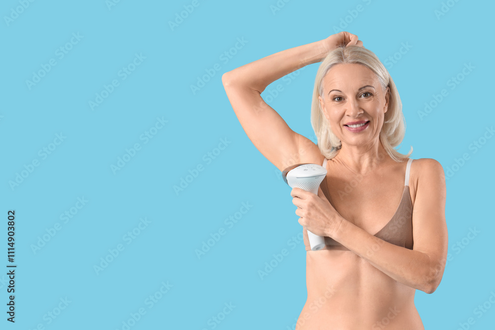 Naklejka premium Mature woman in bra using photoepilator on blue background