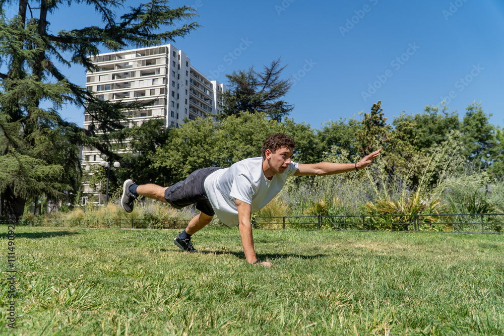 A young man engages in a challenging strength and balance workout, extending one leg and arm in a plank position. The scene showcases focus and fitness dedication