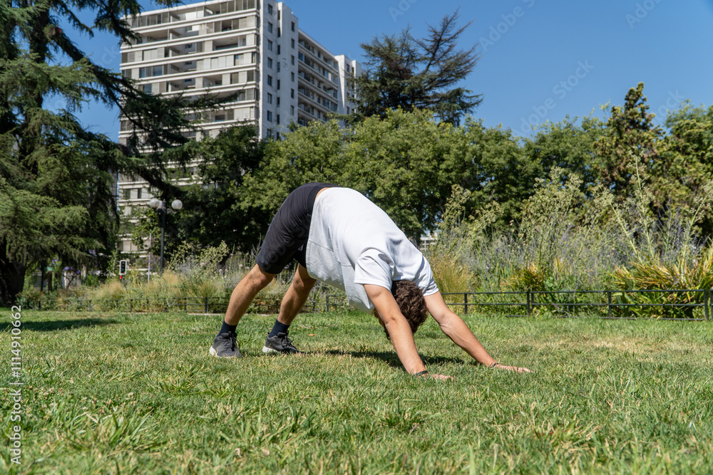 A young man stretches in a sunny park after a workout, surrounded by greenery. The scene captures the essence of post-exercise relaxation and connection with nature.