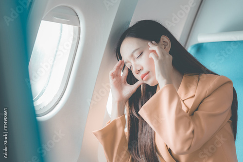 Asian woman gets airsick and has a headache while traveling on the plane, travel concept photo