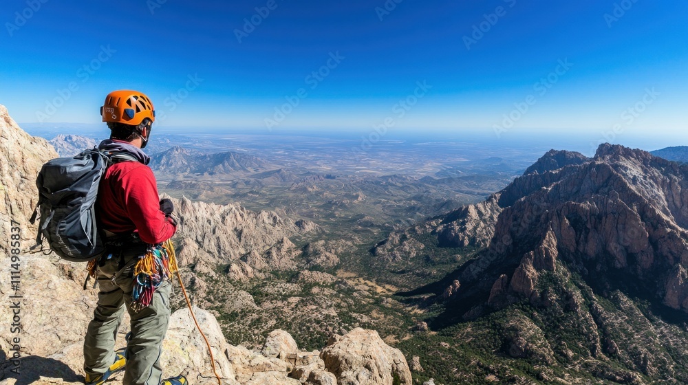 Obraz premium A climber gazes at a vast landscape from a mountain summit, showcasing adventure and nature.