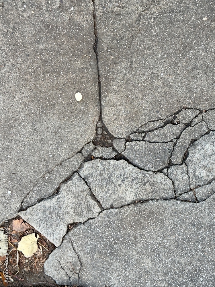Obraz premium Cracked and fragmented broken sidewalk gray pavement 