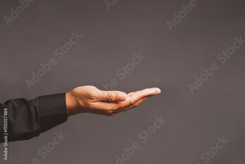 Close-up of an open hand in a black sleeve extended against a plain dark background.