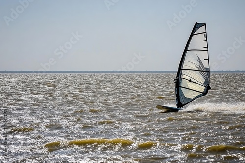 A windsurfer glides across the water, harnessing the wind for sport and leisure. photo