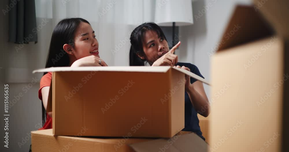 Handheld dolly shot, Two Asian siblings sit on the floor talking as open boxes of items and exchange ideas on how to decorate different corners of new home. Moving and lifestyle concepts. Handheld dolly shot, Two Asian siblings sit on the floor talking as open boxes of items and exchange ideas on how to decorate different corners of new home. Moving and lifestyle concepts.