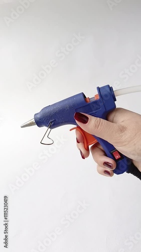 A woman's hand presses the button of the glue gun. Hot glue gun with rods. photo