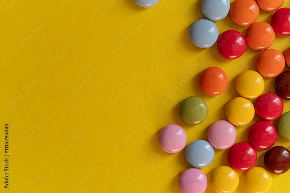 Obraz premium 黄色背景に並ぶカラフルなチョコレート