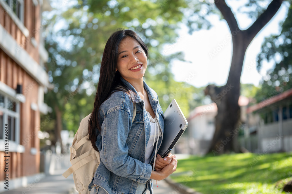 © bongkarn - A cheerful Asian female college student on her way to class, smiling at the camera.