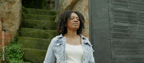 An adult black woman saying hi and going down the stairs in the neighborhood