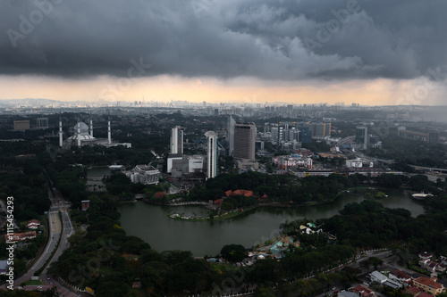 Dark and grey dramatic thunderstorm clouds over the big city with tall buildings and mosque in Asia. 