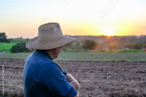 Farmer viewing crops paddocks fields at sunset, working man at end of day, Queensland Australia