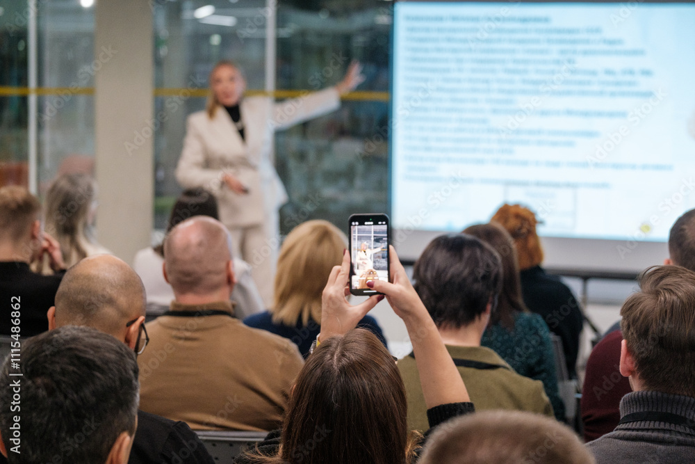 Fototapeta premium Audience in business presentation capturing information with smartphone highlighting modern interaction