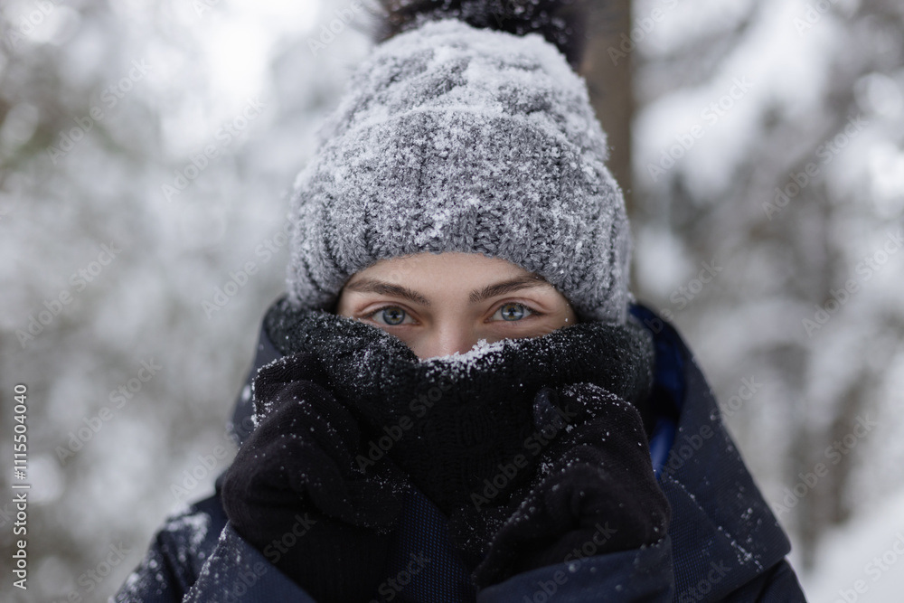 © Cavan Images - Closeup of young woman in scarf and hat covered in snow