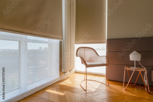 Modern automatic roller blinds and sun shades cover large windows, diffusing natural light into cozy room. Blackout and screen fabrics close-up. Space features stylish chair and minimalist side table.