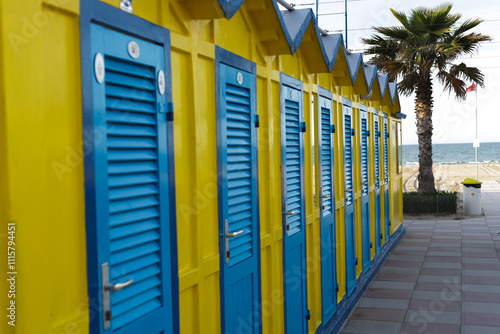 Yellow changing cabin with blue doors on the beach.