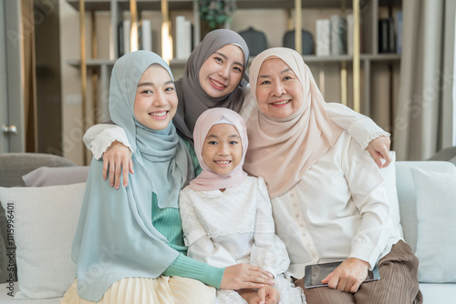 portrait of happy three different generations female muslim family meeting at home,sitting on couch in living room,hugging with love, smile,enjoy holiday time together