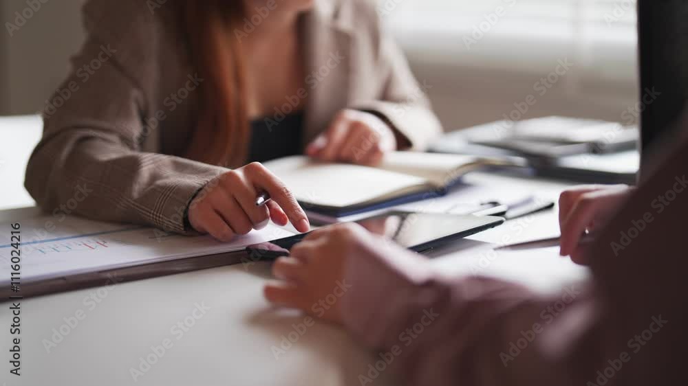 Two businesswomen engaged in a focused discussion, analyzing documents and sharing ideas in a professional office setting with natural light and modern decor Two businesswomen engaged in a focused discussion, analyzing documents and sharing ideas in a professional office setting with natural light and modern decor