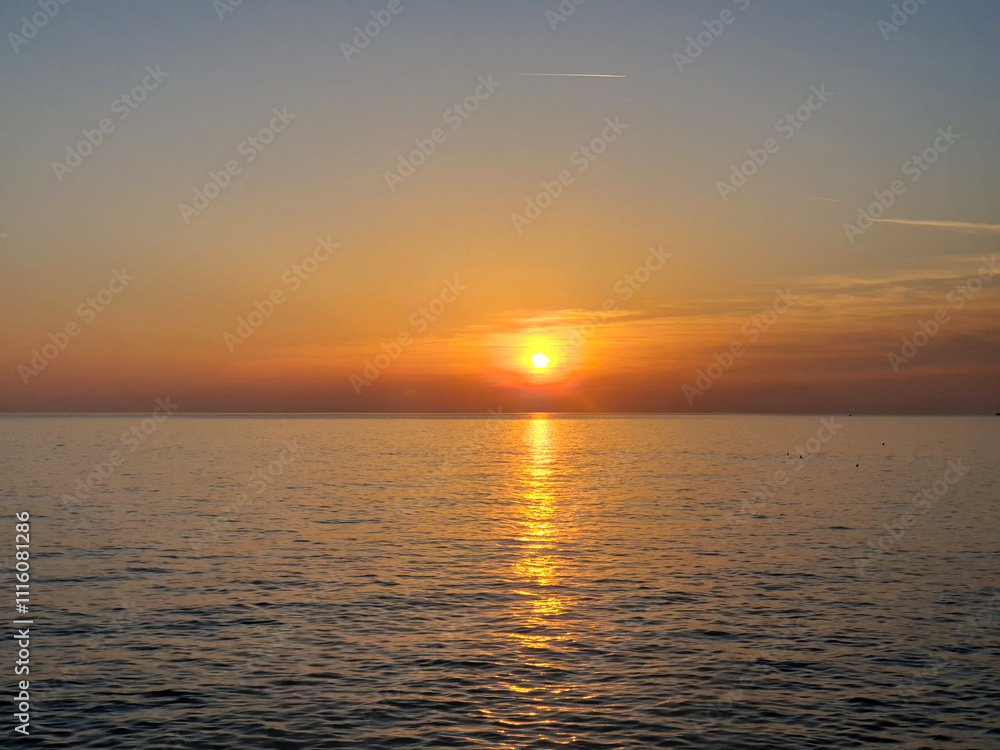 Fototapeta premium A captivating view of the Mediterranean Sea during sunset, with the golden hues of the sun reflecting on the calm waters.