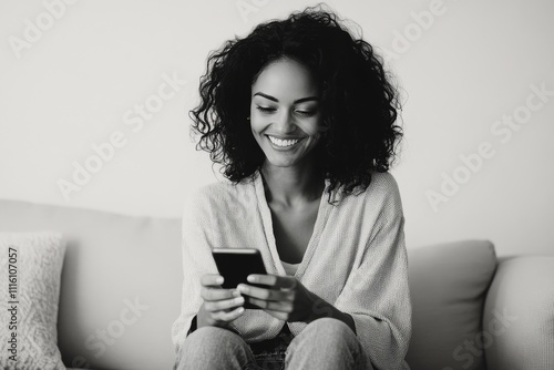 Smiling woman engaging with her smartphone while relaxing on a couch in a coz...