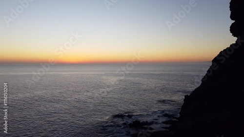 The sea and cliffs of Playa Tasartico, Gran Canaria, Canary Islands, Spain, illuminated by a stunning sunset, captured by a drone. photo