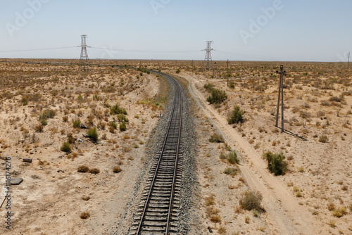 Expansive view of a winding railway through arid desert landscape with power lines nearby. Uzbekistan photo